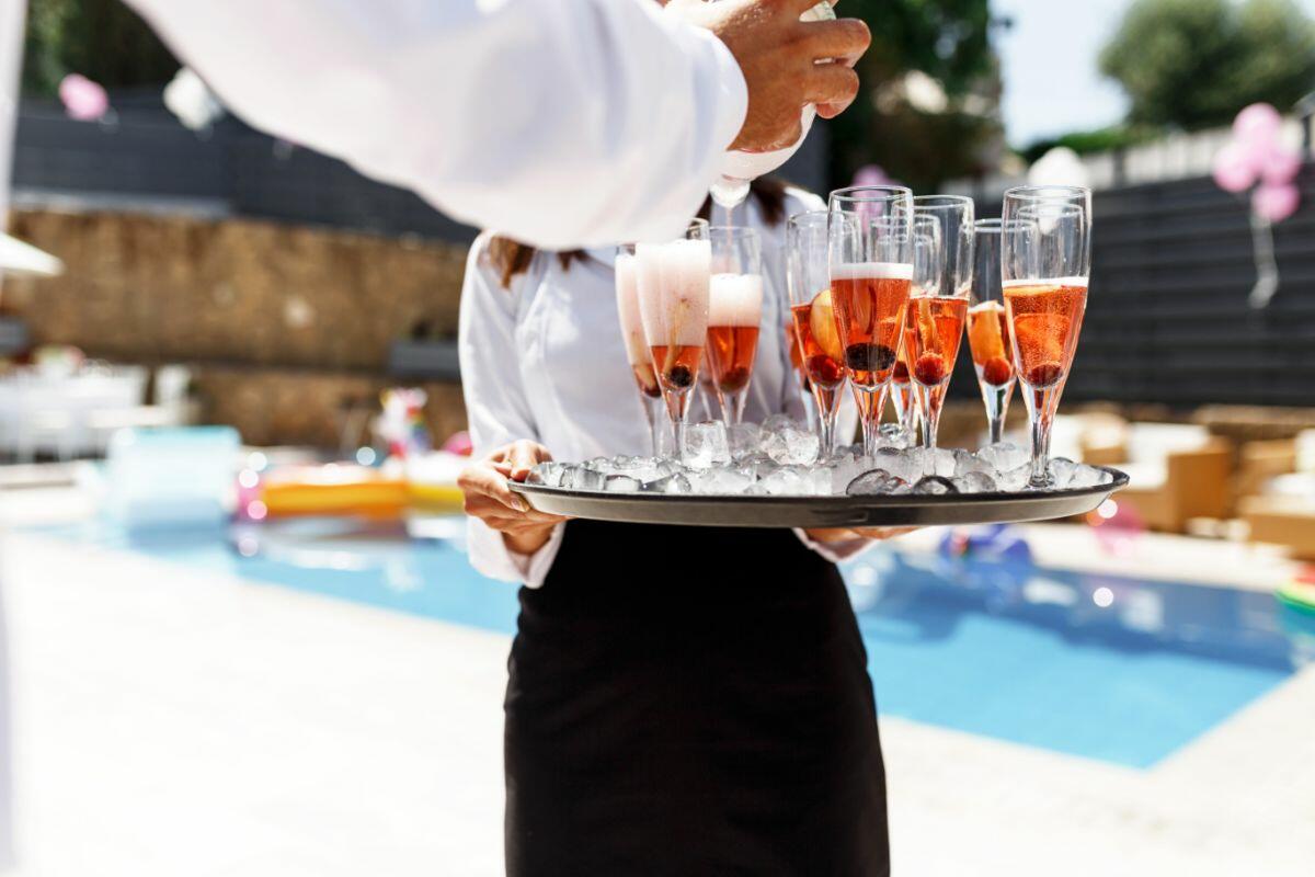 Privatkoch serviert Champagner am Pool einer Luxusvilla auf Ibiza