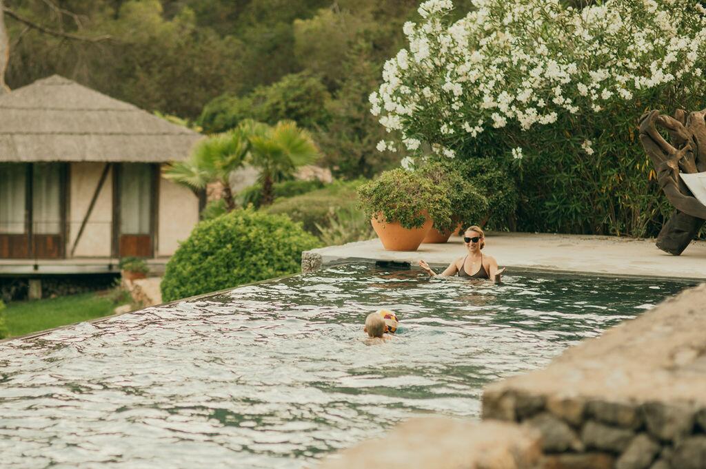 Swimmingpool und mediterraner Garten der Villa Paradiso auf Ibiza, mit Gästen, die das Wasser genießen.