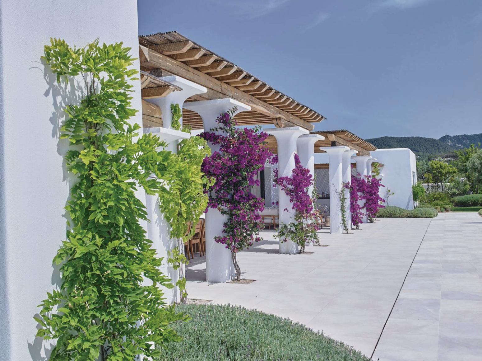 Blakstad Villa auf Ibiza mit weiß getünchten Wänden, Holzpergolen, kletternder Bougainvillea und angelegten Gärten.